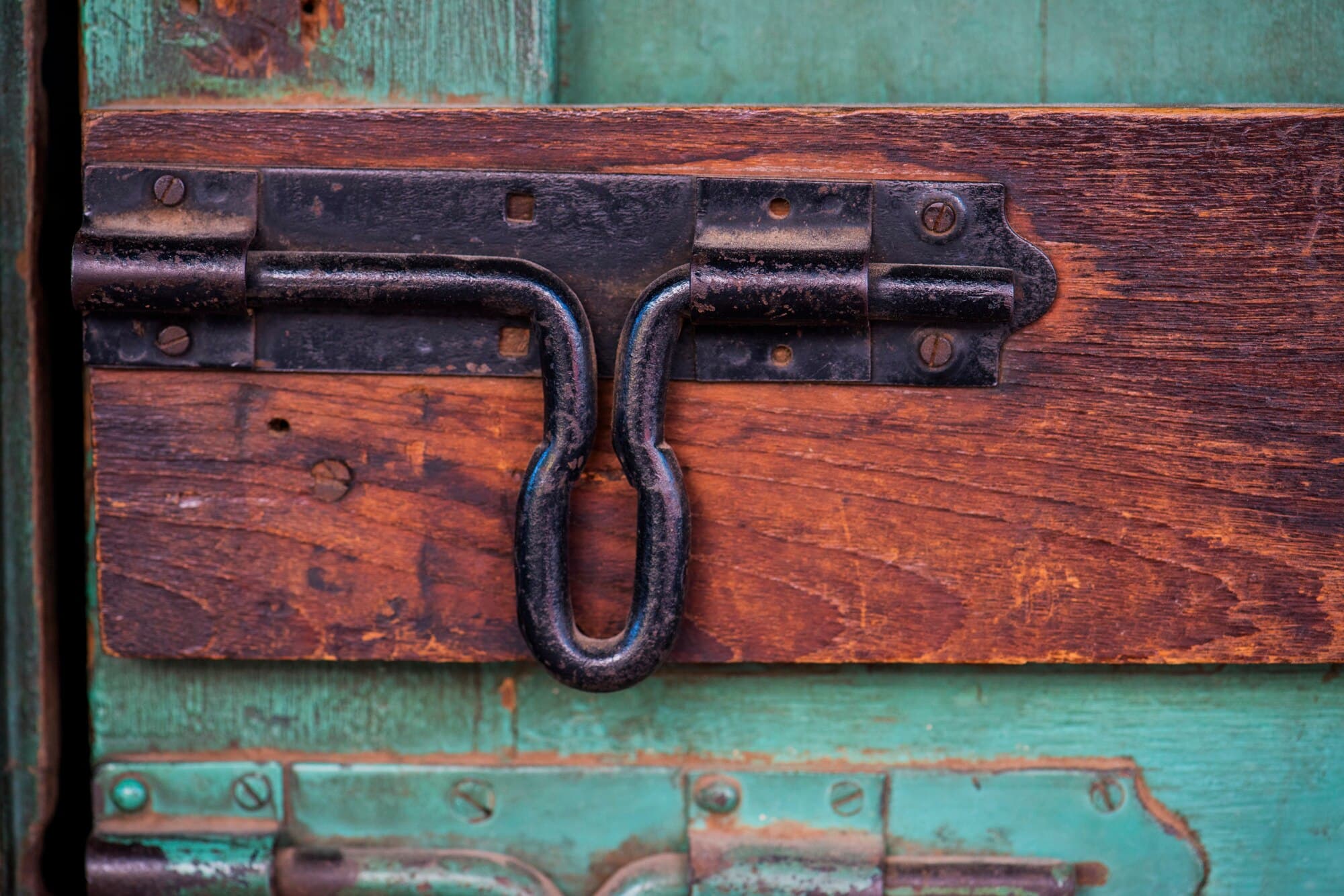 Close-up of a wrought-iron latch on a weathered wooden door